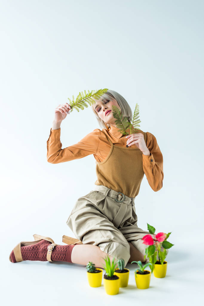 красивая стильная девушка позирует с папоротником листья рядом цветочные горшки на белом
 - Фото, изображение