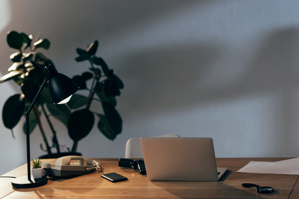 Laptop, smartphone, telefone e arma na mesa no escritório
 - Foto, Imagem