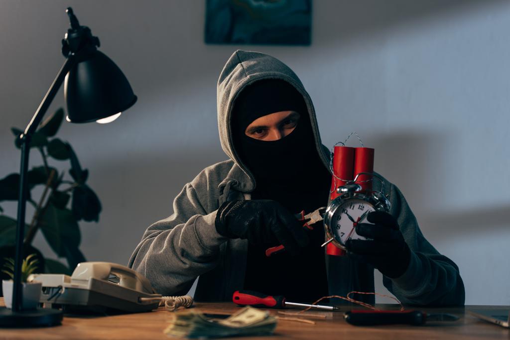 Terrorist mit Maske und Lederhandschuhen bastelt Bombe im Zimmer - Foto, Bild