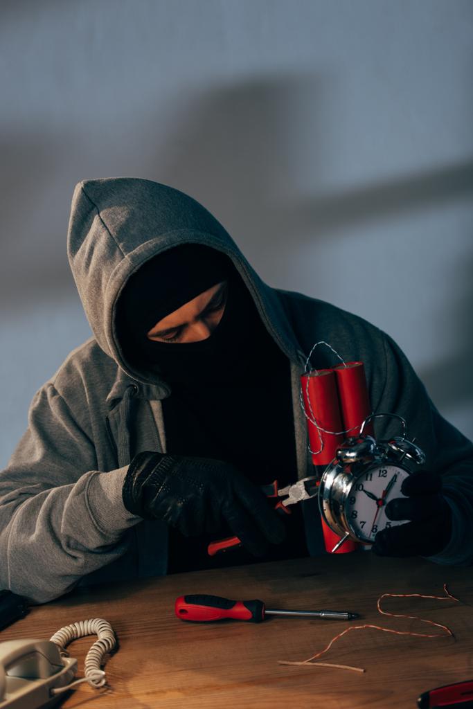 Терорист у масці та рукавичках з плоскогубцями робить бомбу
 - Фото, зображення
