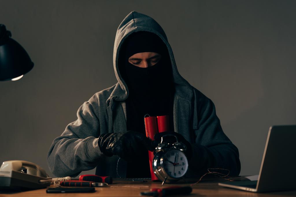 Terrorista concentrado em máscara e luvas pretas fazendo bomba
 - Foto, Imagem