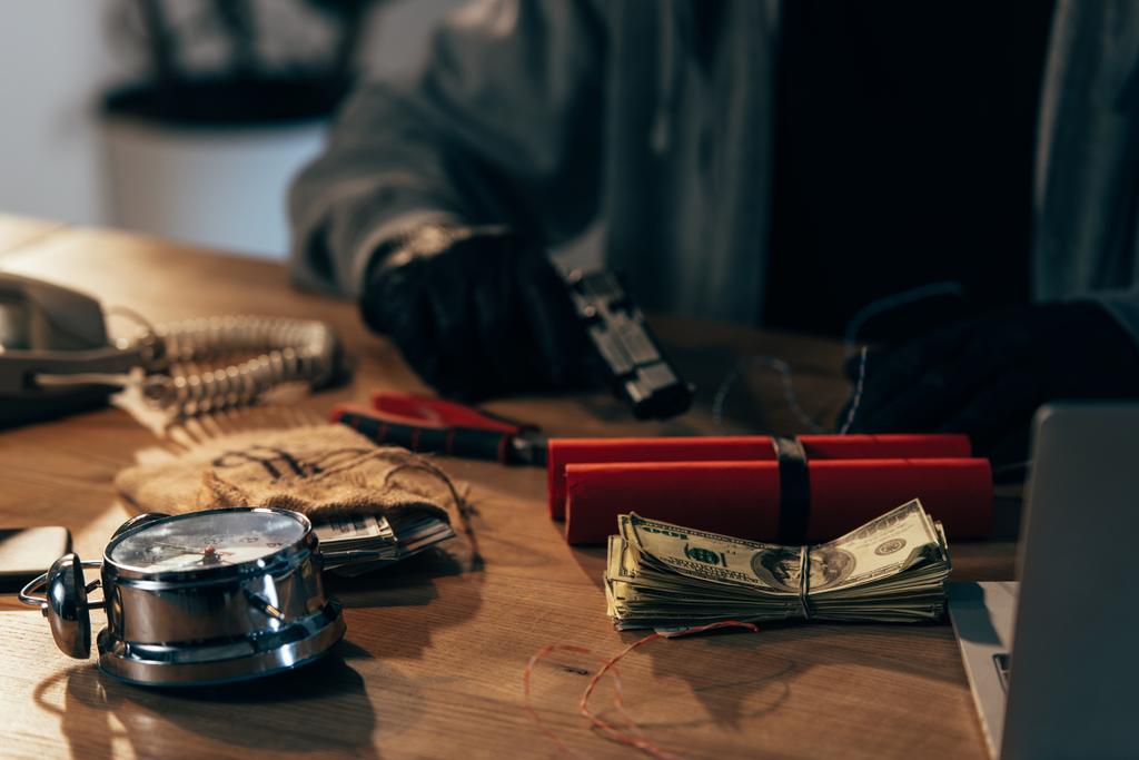 Vista parcial del terrorista sentado a la mesa con dinero y armas
 - Foto, imagen