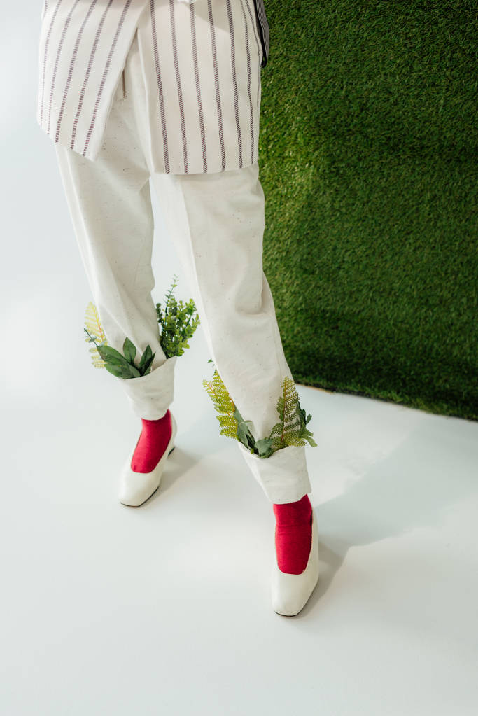 seção baixa de mulher em calças brancas com folhas verdes e sapatos elegantes
  - Foto, Imagem