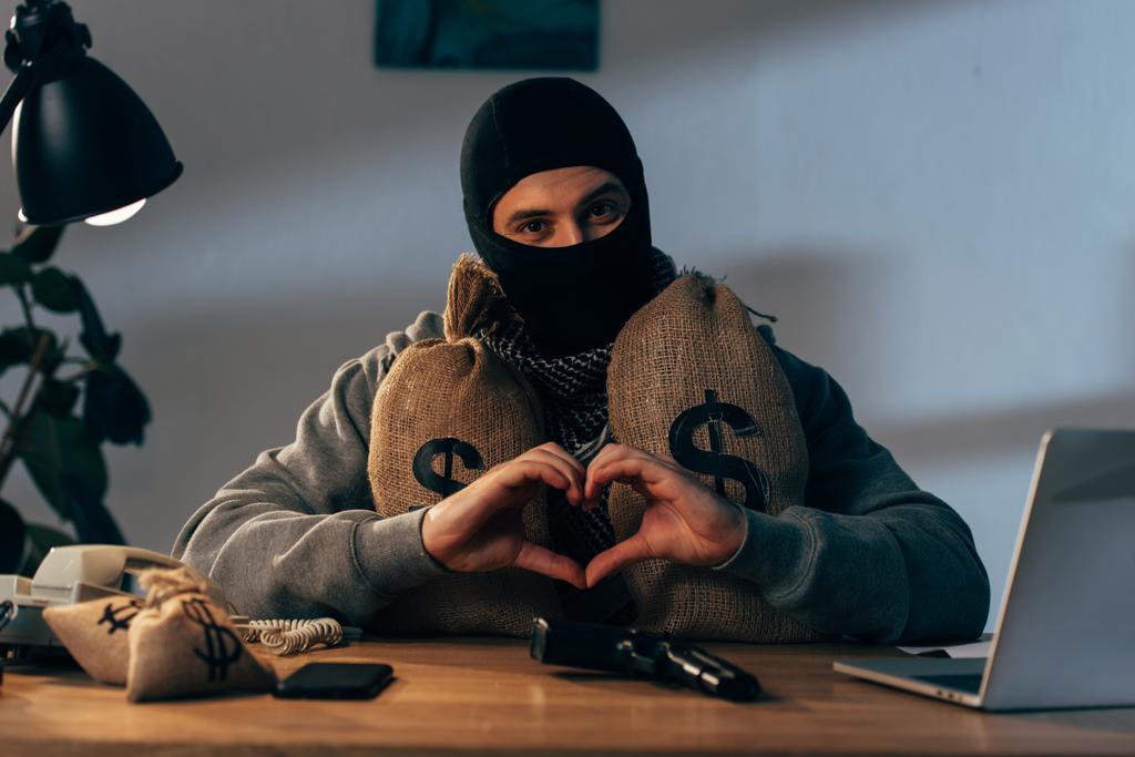 心のサインを示すお金の袋をマスクのテロリスト - 写真・画像