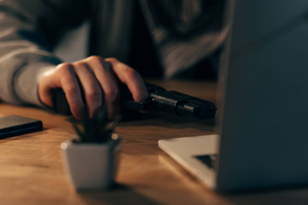 Μερική άποψη της τρομοκρατίας με όπλο που χρησιμοποιούν φορητό υπολογιστή στο τραπέζι - Φωτογραφία, εικόνα