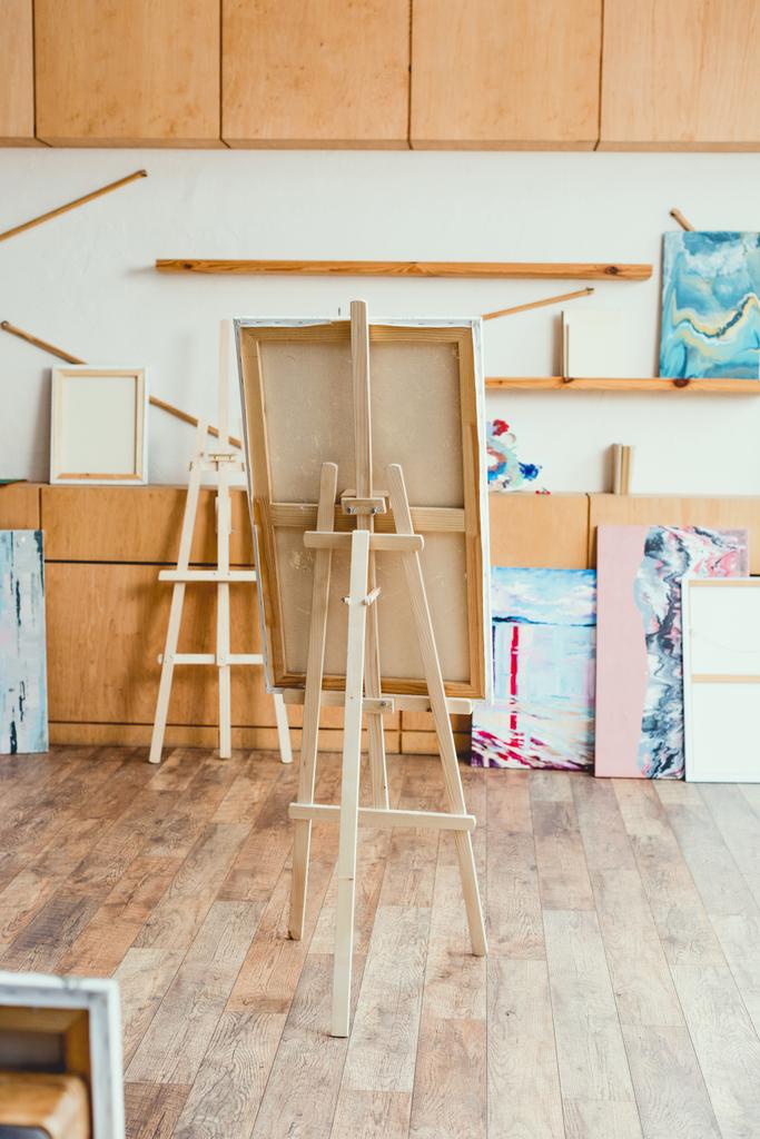 estúdio de pintura leve espaçoso com armários de madeira, cavaletes e pinturas
 - Foto, Imagem