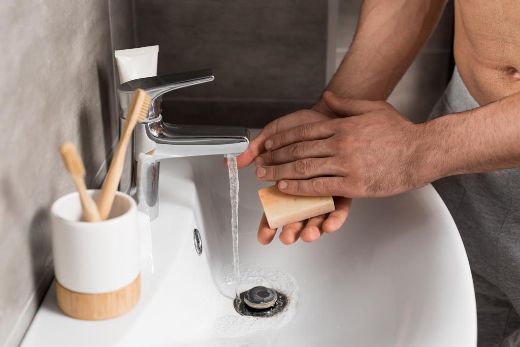Widok człowieka trzymającego mydło podczas mycia rąk w łazience  - Zdjęcie, obraz