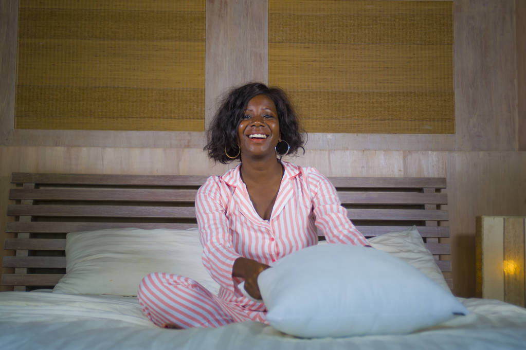 mladá šťastná a krásná africká americká Černoška v pyžamu ležící uvolněně a hravé na posteli s úsměvem, veselé a pozitivní probuzení ráno optimistické a čerstvé - Fotografie, Obrázek