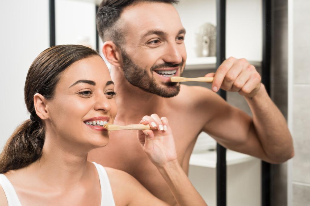 fidanzato allegro e attraente ragazza lavarsi i denti in bagno
  - Foto, immagini