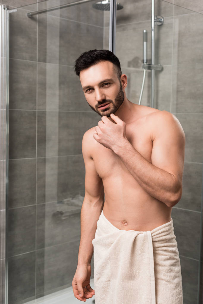 Nachdenklicher muskulöser Mann steht im modernen Badezimmer  - Foto, Bild