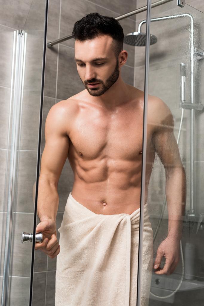 μυϊκή όμορφος άνδρας στέκεται στην καμπίνα ντους στο μπάνιο  - Φωτογραφία, εικόνα