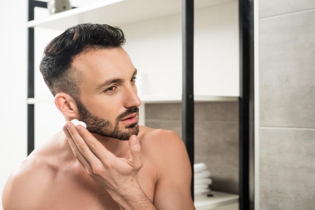 красивий бородатий чоловік наносить піну для гоління на обличчя у ванній
  - Фото, зображення