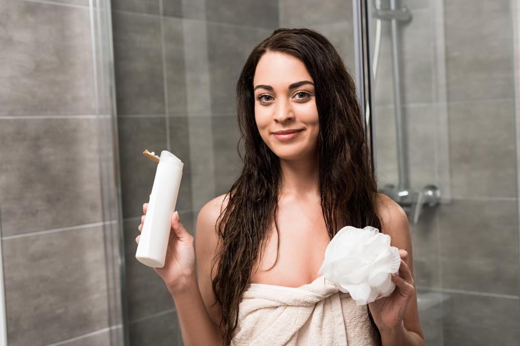 Veselá brunetka žena držící sprchový gel a houbu v rukou  - Fotografie, Obrázek