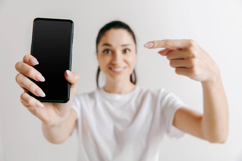 Портрет уверенной девушки с пустым экраном мобильного телефона
 - Фото, изображение