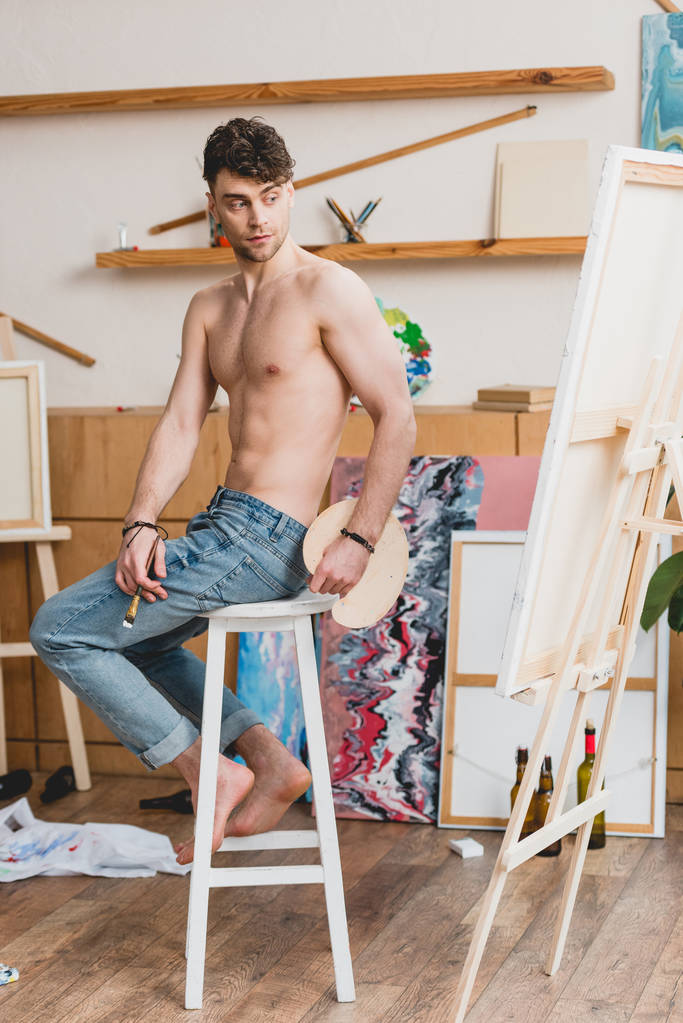 Galeri yüksek sandalyede otururken yakışıklı yarı çıplak sanatçı - Fotoğraf, Görsel