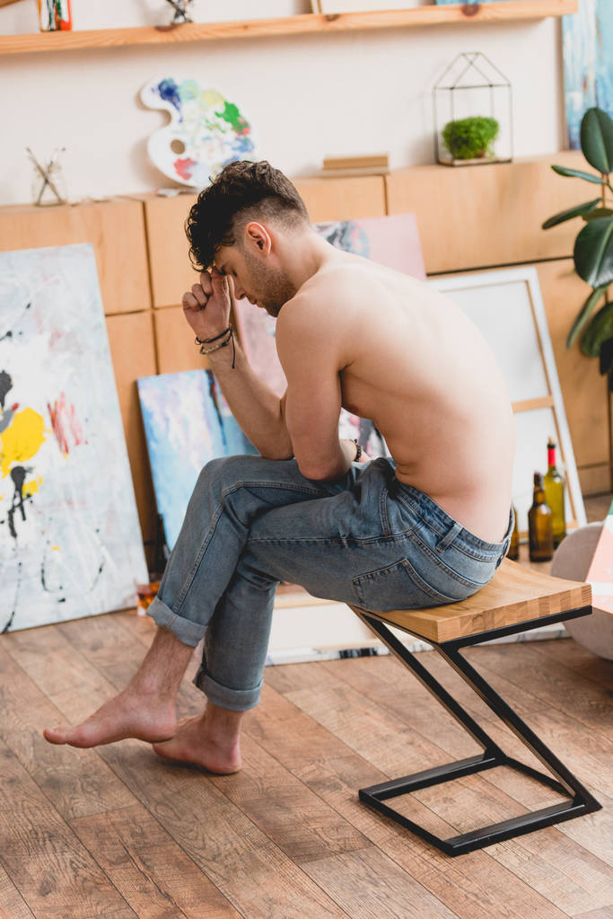 tired half-naked artist sitting on chair in painting studio - Photo, Image