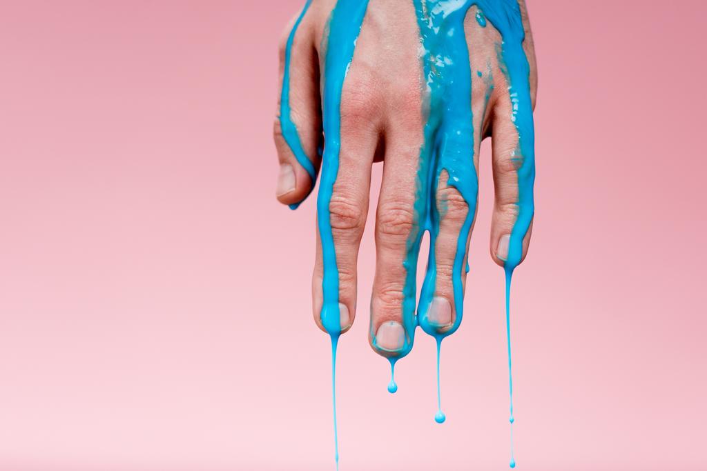 обрізаний вид людини з рукою в синій фарбі розливається на рожевому
 - Фото, зображення