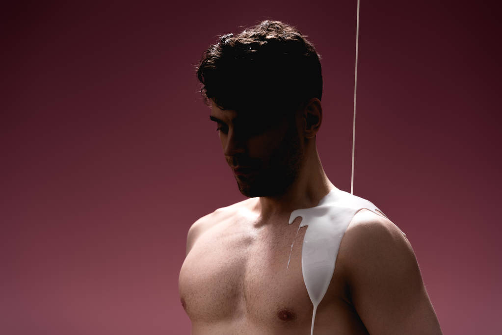 Selbstbewusster Mann mit weißer Farbe verschüttet Körper auf lila - Foto, Bild