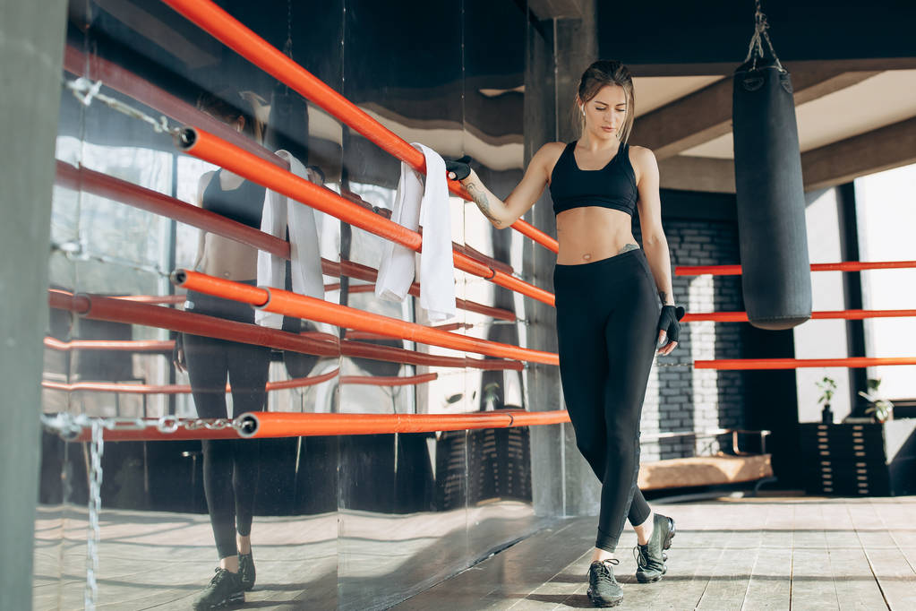 Mädchen in modischem Top und Leggings posieren in der Halle. Fitness-Model mit schöner Sportfigur für Werbebekleidung und gesunde Ernährung - Foto, Bild