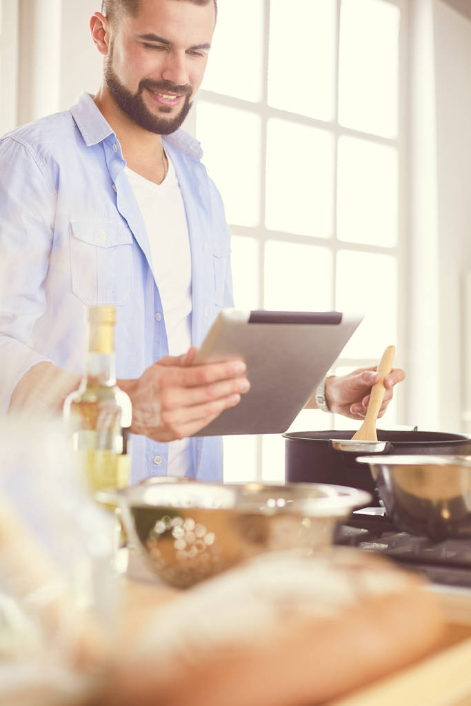 Человек по рецепту на цифровой планшет и приготовление вкусной и здоровой пищи на кухне в домашних условиях - Фото, изображение