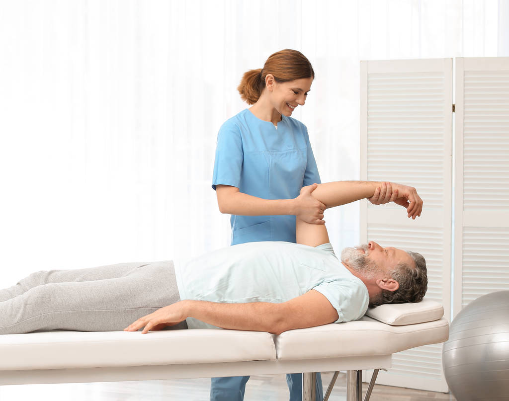 Fysiotherapeut werken met de patiënt in de kliniek. Revalidatie-therapie - Foto, afbeelding
