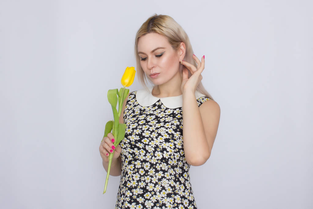 blonde Frau hält eine gelbe Tulpe in der Hand - Foto, Bild