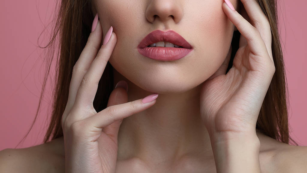 Portret van de schoonheid van de jonge vrouw met de bloem. Model meisje met professionele make-up en Nail art manicure op roze achtergrond. - Foto, afbeelding