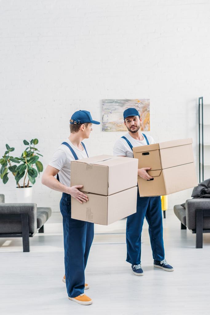 dva stěhovací skříně v uniformě s lepenkovou krabicí v bytě s prostorem pro kopírování - Fotografie, Obrázek