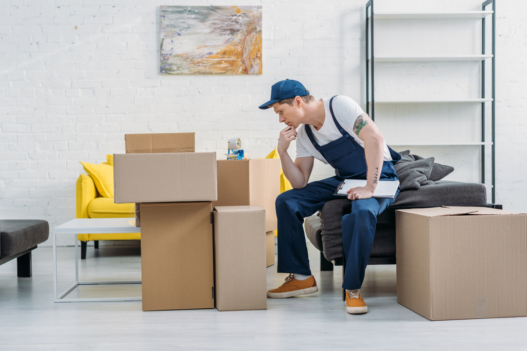 застенчивый мовер, сидящий у картонных коробок и держащий буфер обмена в квартире
 - Фото, изображение