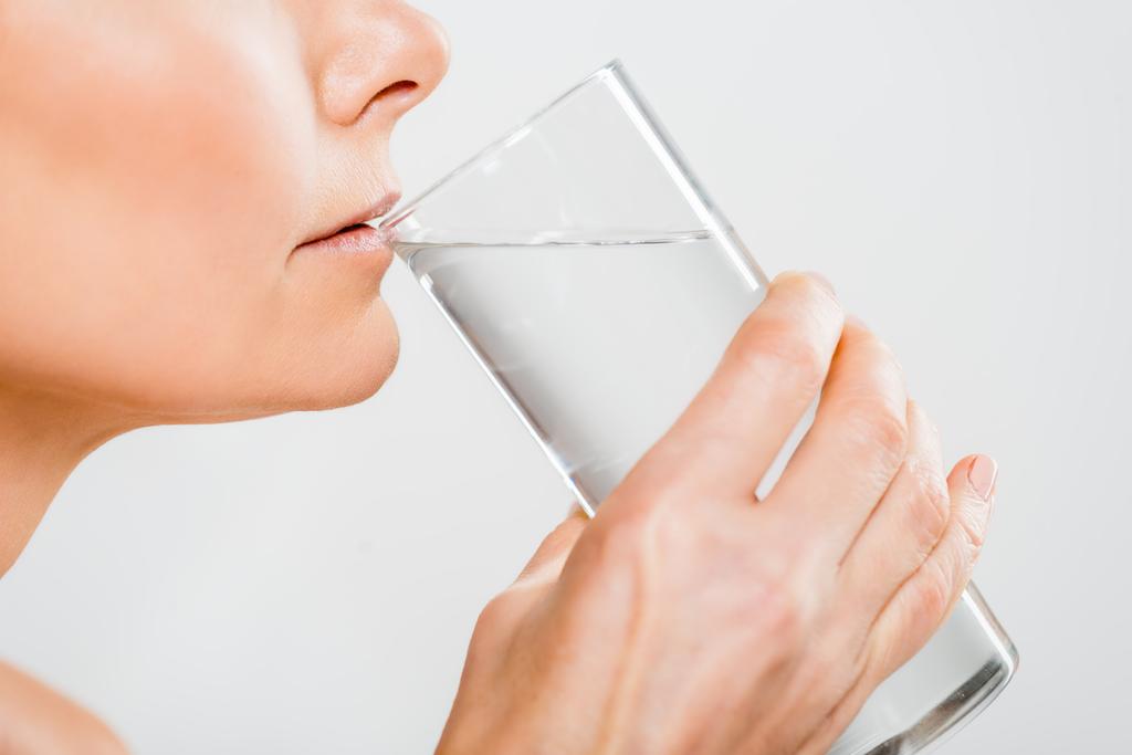 vista cortada de mulher madura bebendo água de vidro isolado em cinza
  - Foto, Imagem