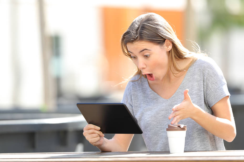 Chica adolescente asombrada usando una tableta sentada en un parque
 - Foto, Imagen