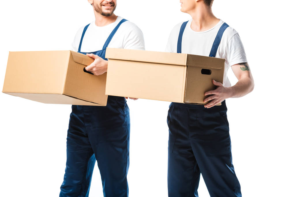 bijgesneden weergave van twee verhuizers vervoeren kartonnen dozen geïsoleerd op wit - Foto, afbeelding
