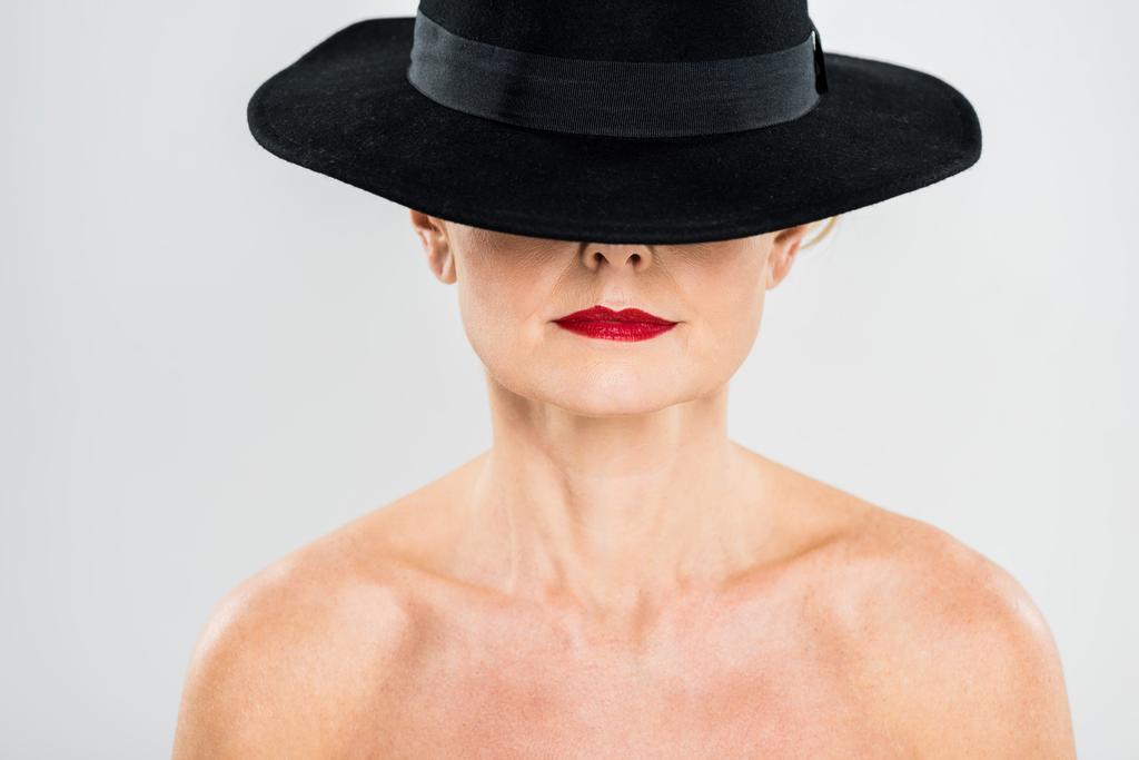 middle aged elegant and fashionable woman with red lips in black hat isolated on grey  - Photo, Image