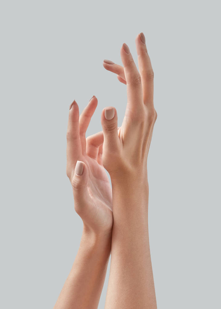 Zamknij się obraz piękna kobieta ręce z lekka manicure na paznokcie na szarym tle. Kremy do rąk, zabiegów manicure. Miejsce dla tekstu. - Zdjęcie, obraz