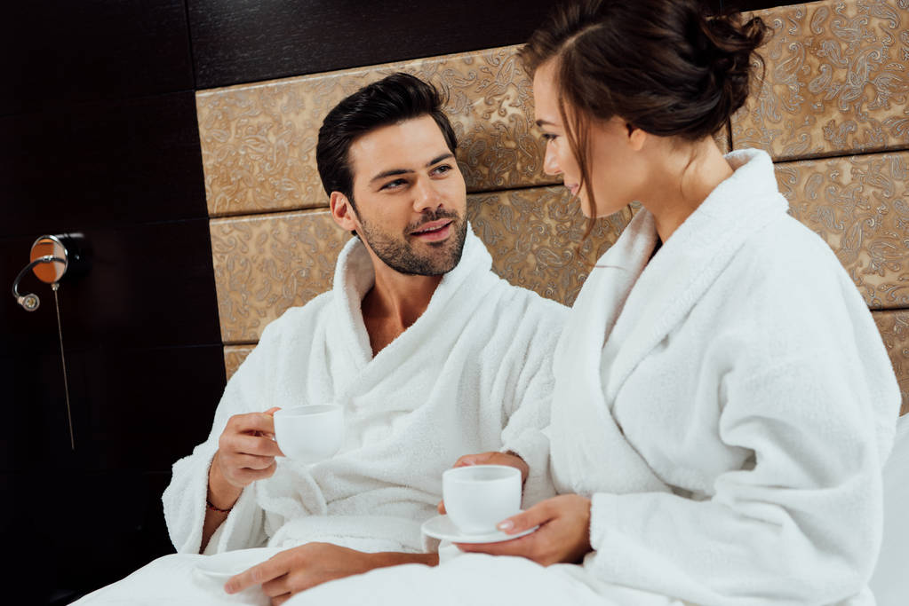 handsome man looking at attractive woman in bathrobe with cup of coffee  - Photo, Image