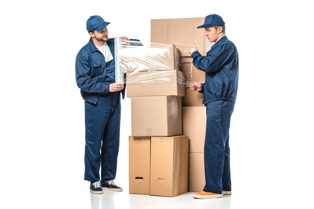zwei Mover wickeln Kartons mit einer Rolle Stretchfolie auf weiß - Foto, Bild