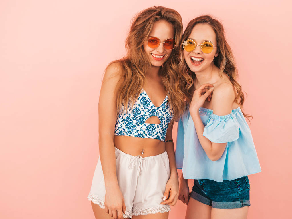 Dos jóvenes hermosas chicas hipster sonrientes en ropa hipster de verano de moda. Sexy mujeres despreocupadas posando sobre fondo rosa. Modelos positivos divirtiéndose
 - Foto, imagen