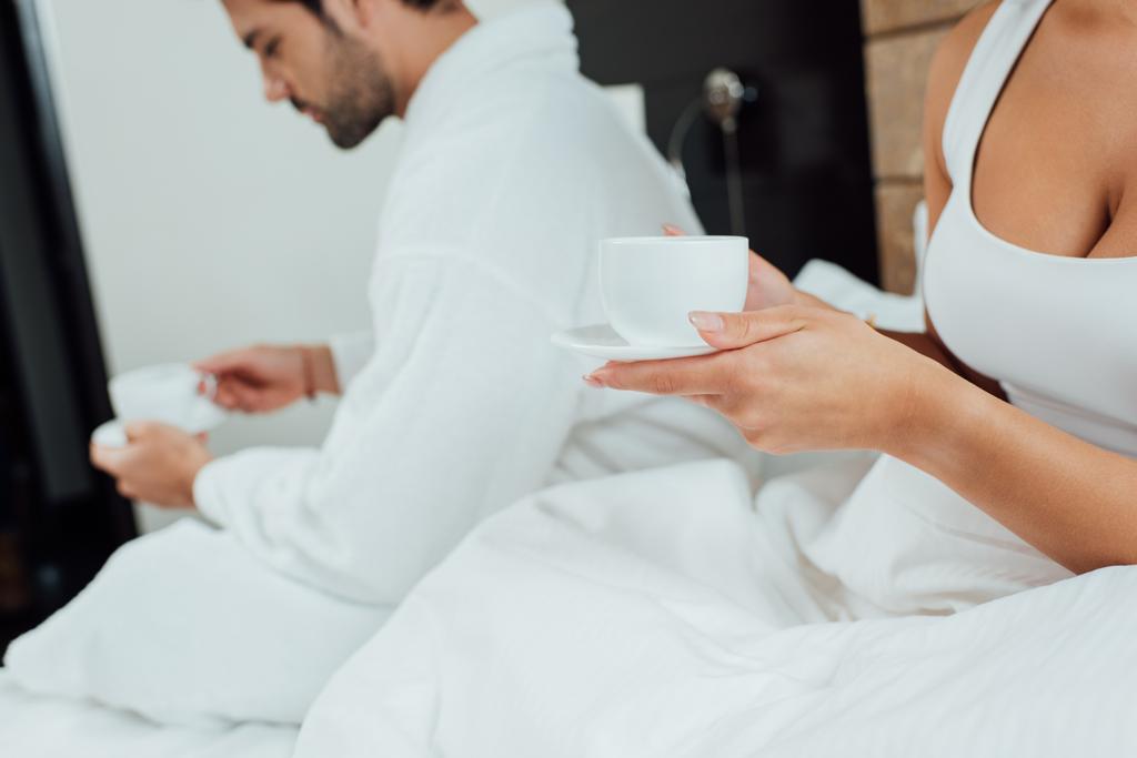 女と男とベッドでのコーヒー カップを保持しているのビューをトリミング - 写真・画像