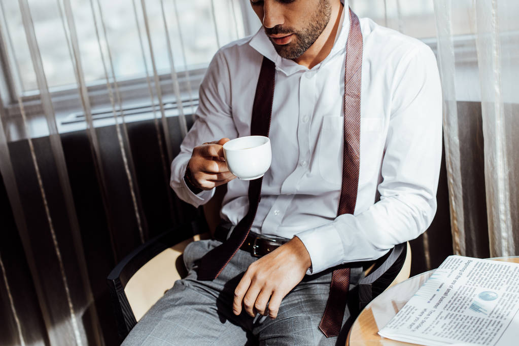 bir fincan kahve tutan takım elbiseli sakallı adam kırpılmış görünümü - Fotoğraf, Görsel