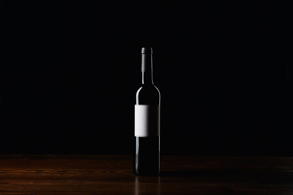 Butelka wina z pustą etykietę na powierzchni drewnianych na czarnym tle - Zdjęcie, obraz