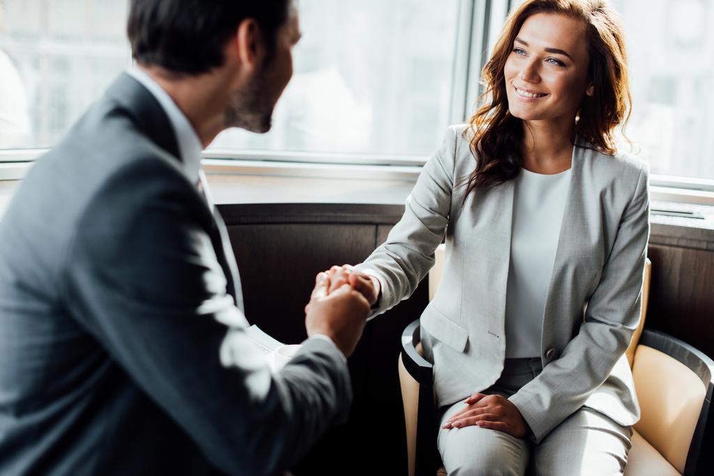 selective focus of happy businesswoman shaking hands with businessman  - Photo, Image