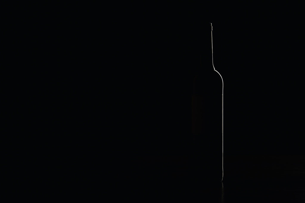 Silhouet van glazen flesje met wijn op zwart - Foto, afbeelding