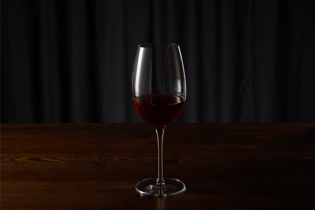 Склянка з червоним вином на дерев'яній поверхні на темному
 - Фото, зображення