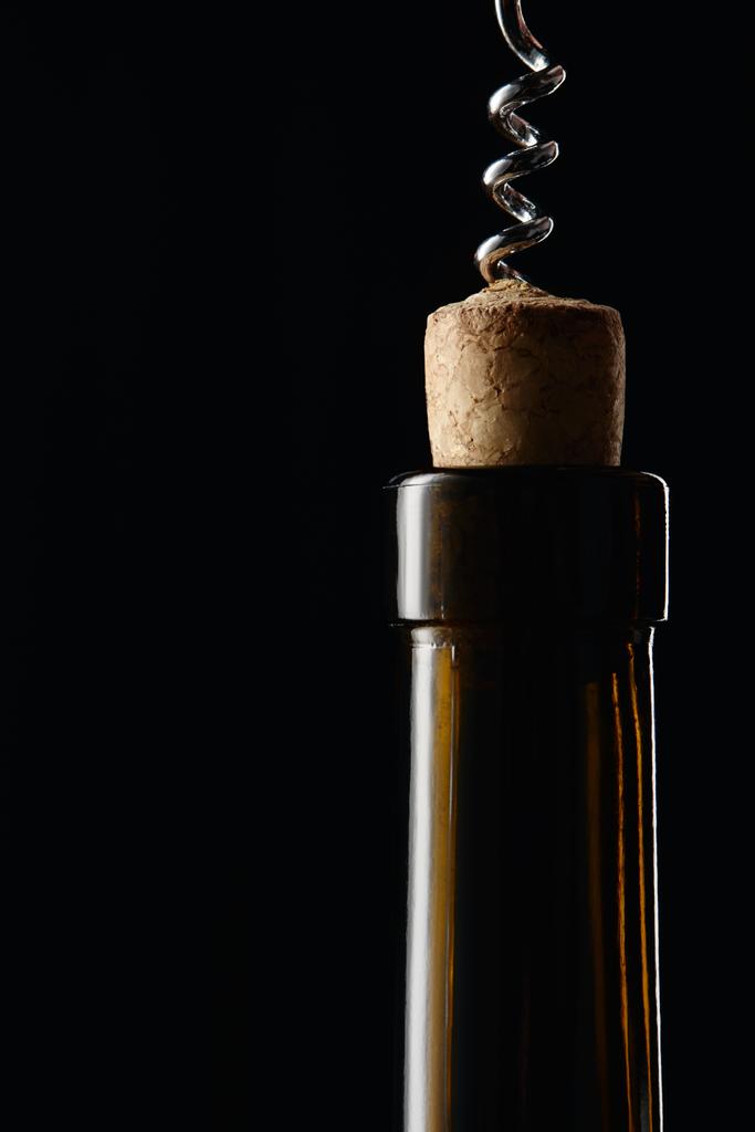 Glass wine bottle with wooden cork and corkscrew isolated on black - Photo, Image