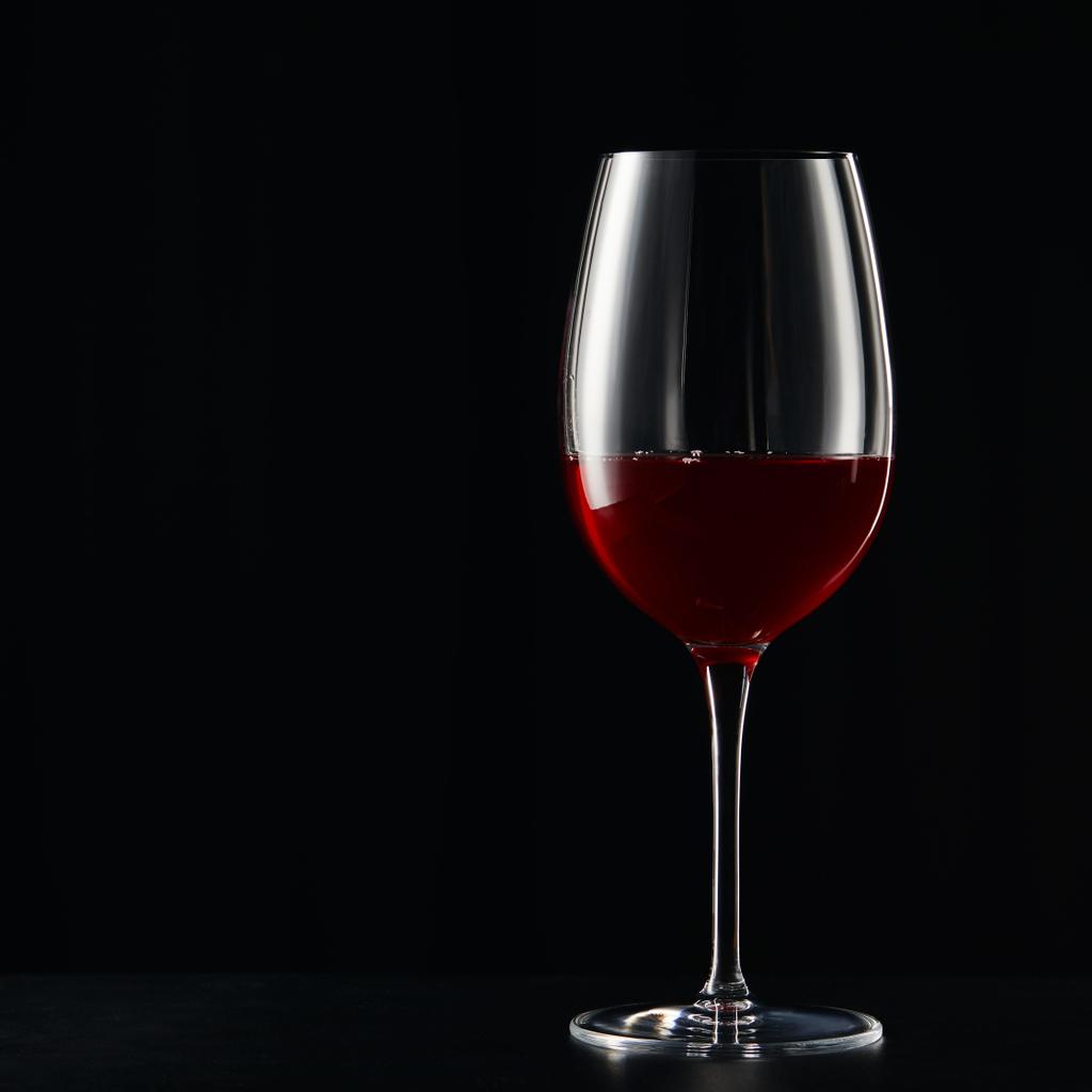 Copa de vino con vino tinto en la superficie oscura aislado en negro
 - Foto, imagen