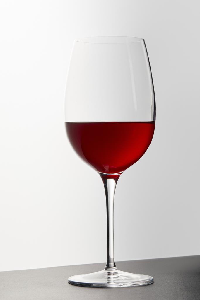 Wine glass with red wine on dark surface on white - Photo, Image