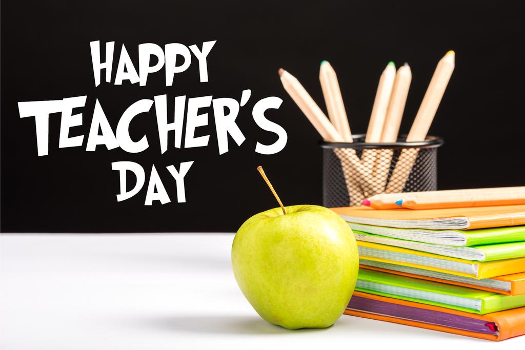 黒地幸せな先生の日レタリングが付いてテーブルに新鮮なリンゴ、ノートブックおよび色鉛筆  - 写真・画像