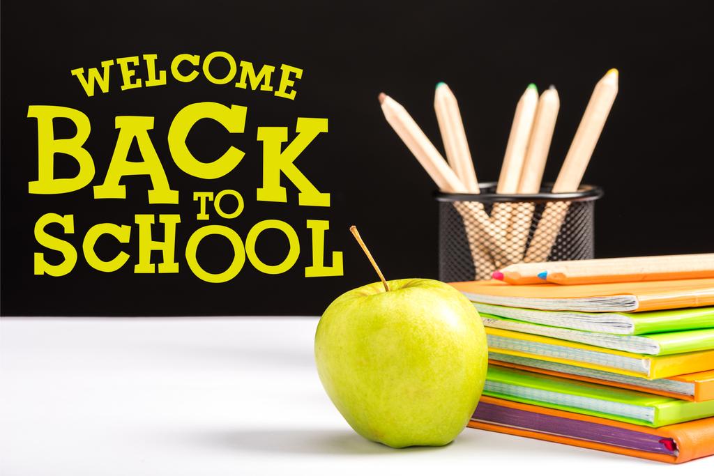 świeże apple, Notebooki i kolor kredki na stole z Witamy z powrotem do szkoły napis na czarnym tle  - Zdjęcie, obraz
