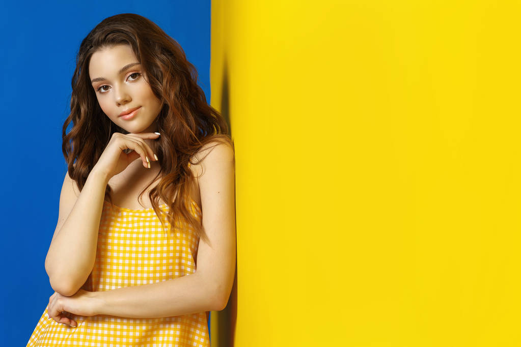 junge Frau in gelbem Sarafan posiert vor blauem Hintergrund - Foto, Bild