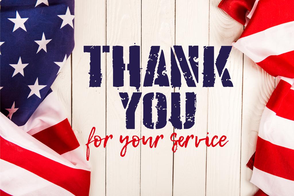 Draufsicht auf amerikanische Flaggen und Danke für Ihren Service-Schriftzug auf weißer Holzoberfläche - Foto, Bild